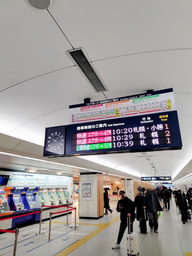 新千歳空港駅 発車時刻掲示板と改札口付近 駅構内の人々