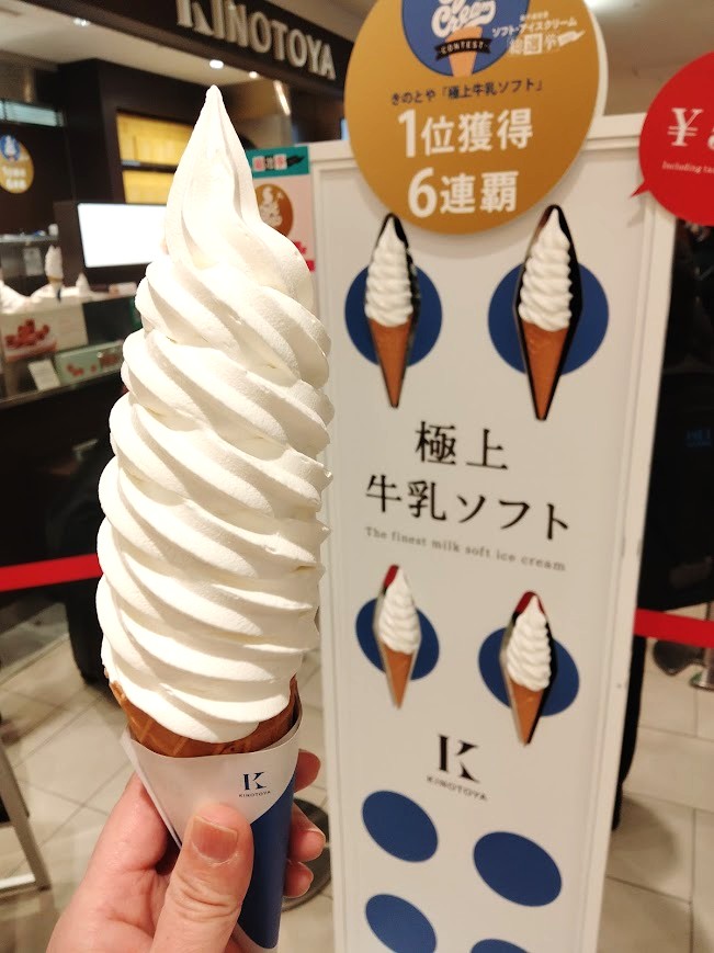 KINOTOYA　極上牛乳ソフト　店舗の看板の前で手に持つ