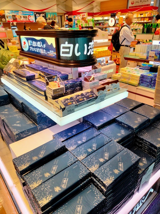 新千歳空港保安検査後エリアJALプラザ店内 白い恋人 店内でお土産を選ぶ人々