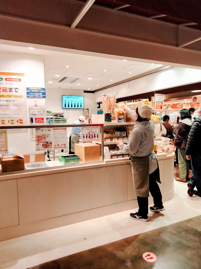店舗正面 列へ並ぶ人と店舗の整理をする店員